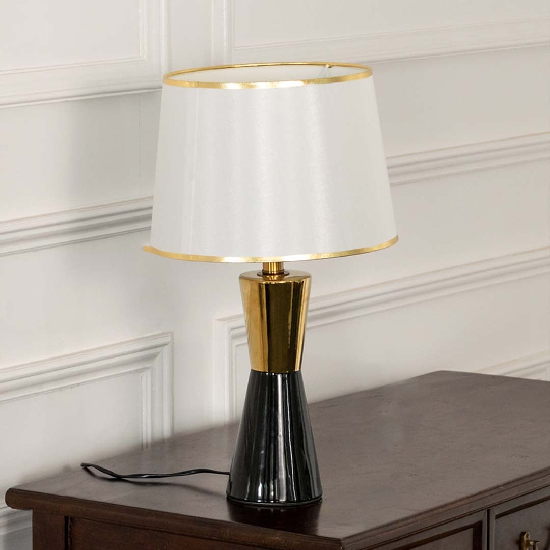 White pleated shade black and gold table lamp on wooden sideboard with light off for chic modern décor.