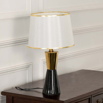 White pleated shade black and gold table lamp on wooden sideboard with light off for chic modern décor.