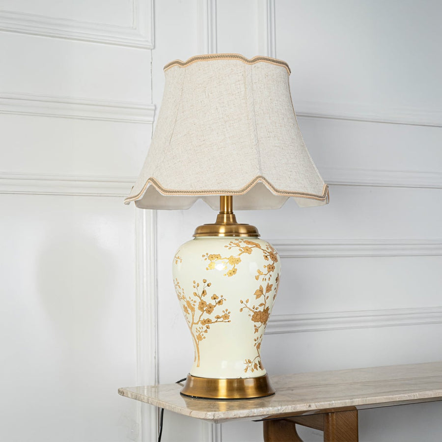 Table lamp with cream ceramic base and gold floral design displayed on a white background for clear product viewing.