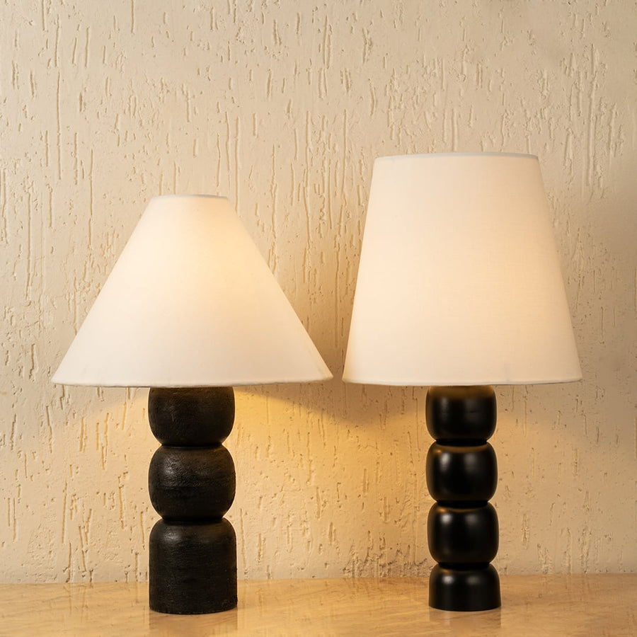 Pair of black wood table lamps with white fabric shades casting warm ambient light for bedroom and living room decor.