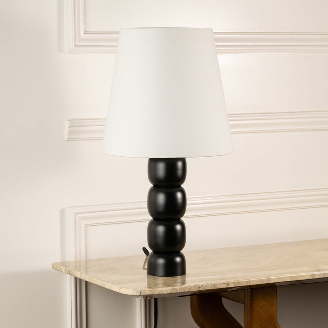 White fabric shade table lamp with black turned wood base and brass accents for timeless interior decor styling.