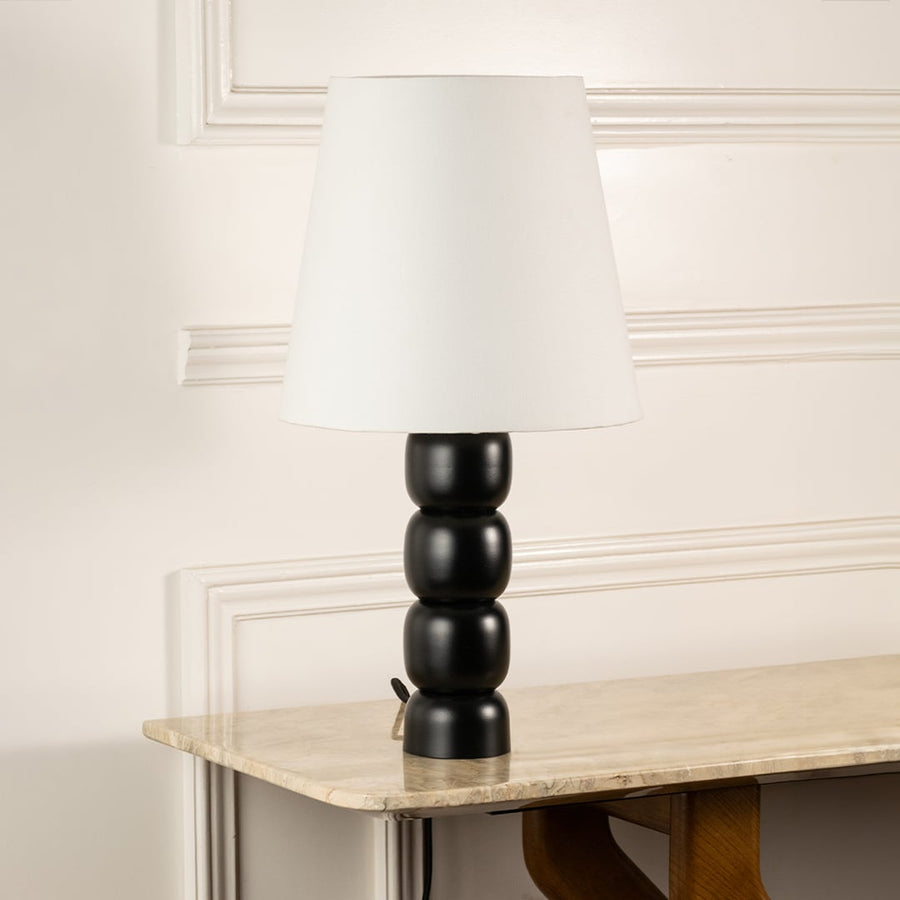 White fabric shade table lamp with black turned wood base and brass accents for timeless interior decor styling.