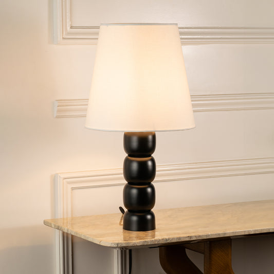 Table lamp with white fabric shade and black sculpted base ideal for bedroom or living room table decor styling on clean background.