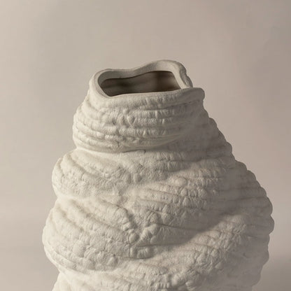Closeup of handcrafted white ceramic sculptural vase with artistic textured details perfect for modern home table decoration.