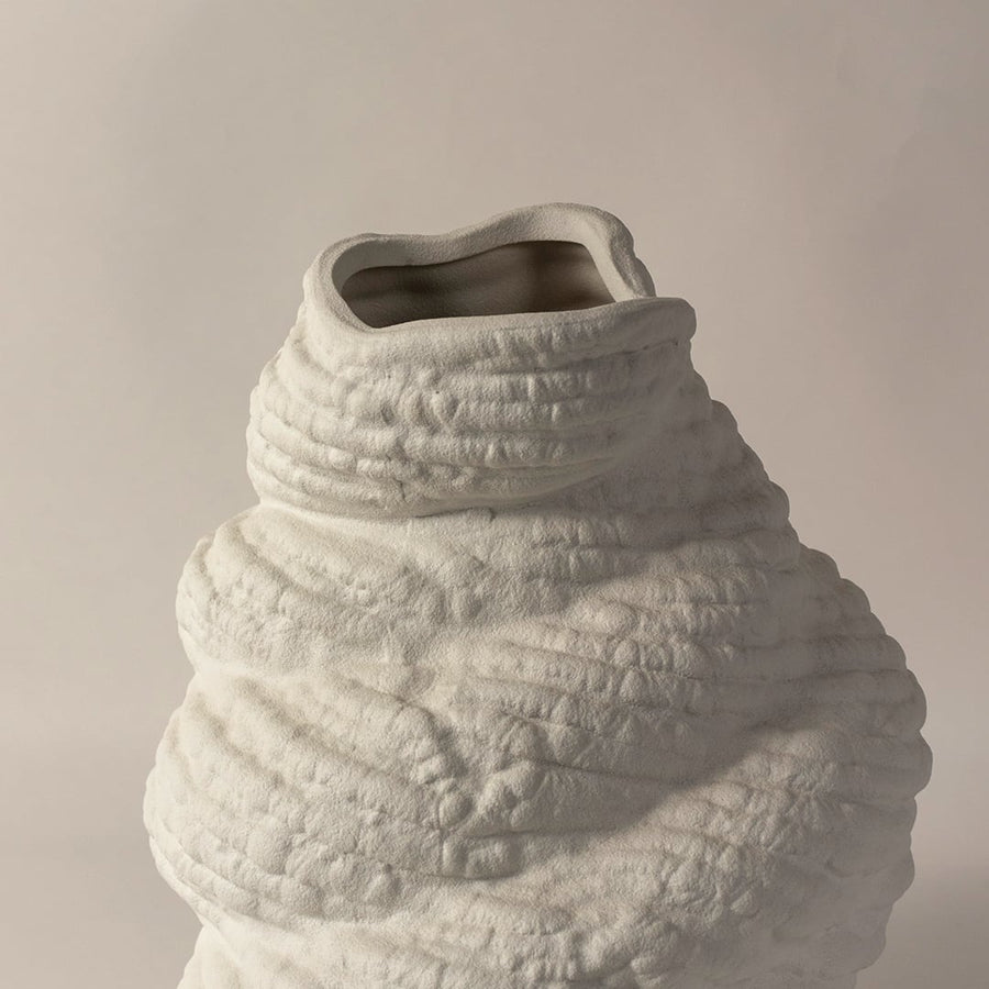 Closeup of handcrafted white ceramic sculptural vase with artistic textured details perfect for modern home table decoration.