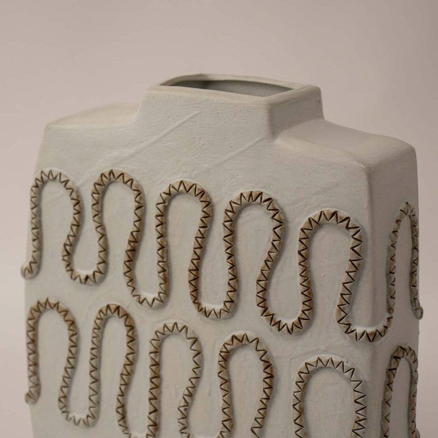 Decorative white ceramic vase with textured loop design placed on white surface against neutral background enhancing modern sculptural home decor appeal.