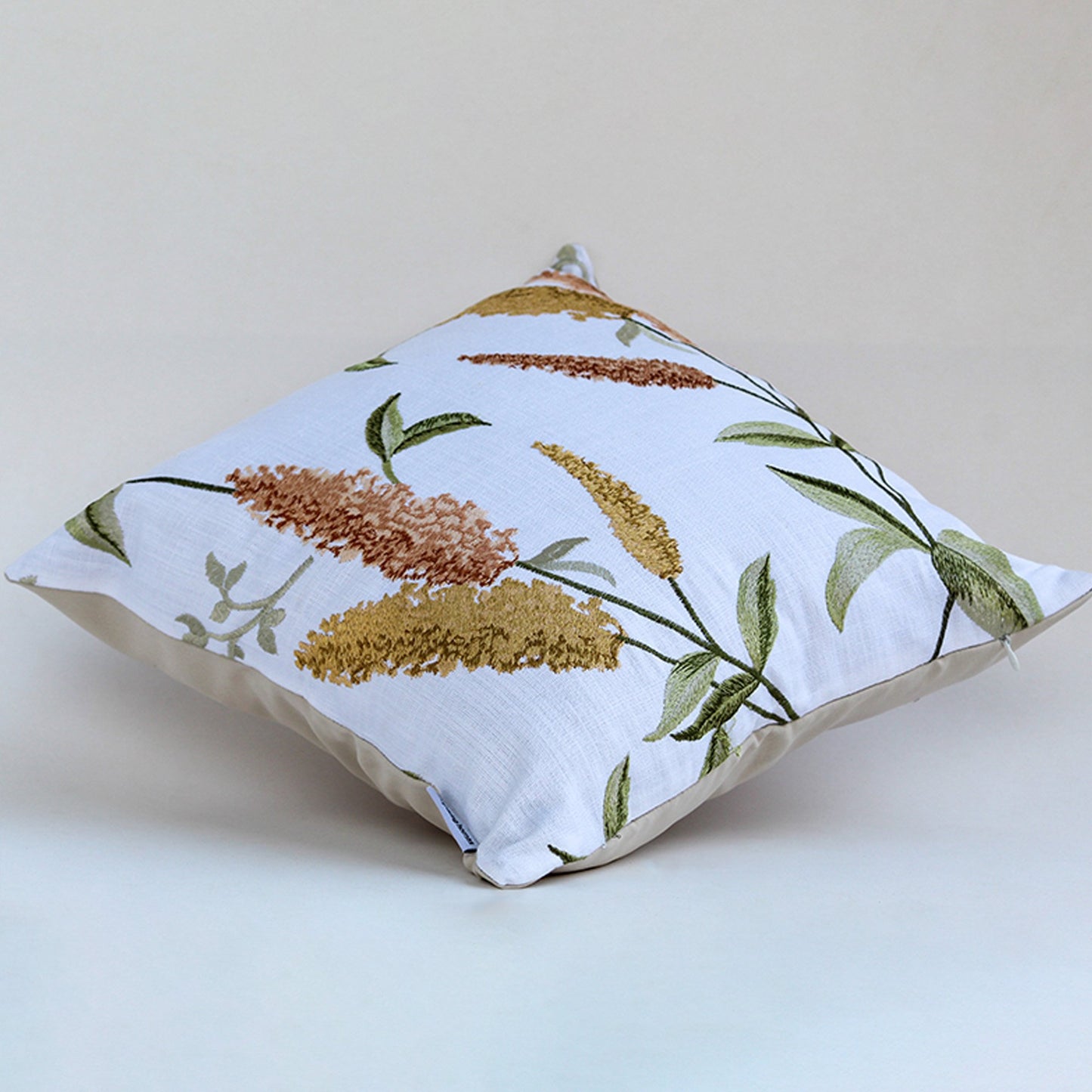Soft square cushion with botanical floral print featuring earthy brown and mustard leaves on a light off white fabric background styled for home decor