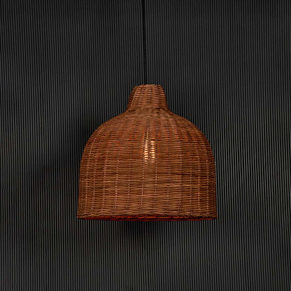 Rattan pendant light glowing on black background with natural wicker dome shade for rustic boho style interiors.