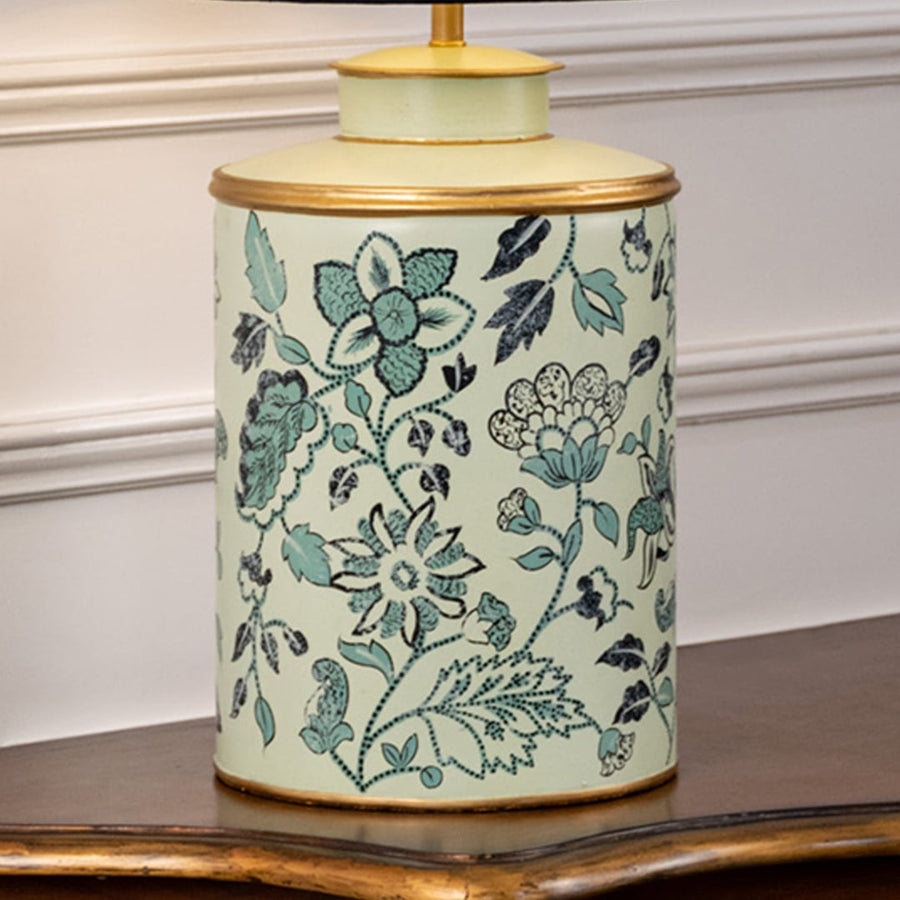Table lamp closeup displaying floral motif on ceramic base with teal shades intricate detailing and glossy surface.