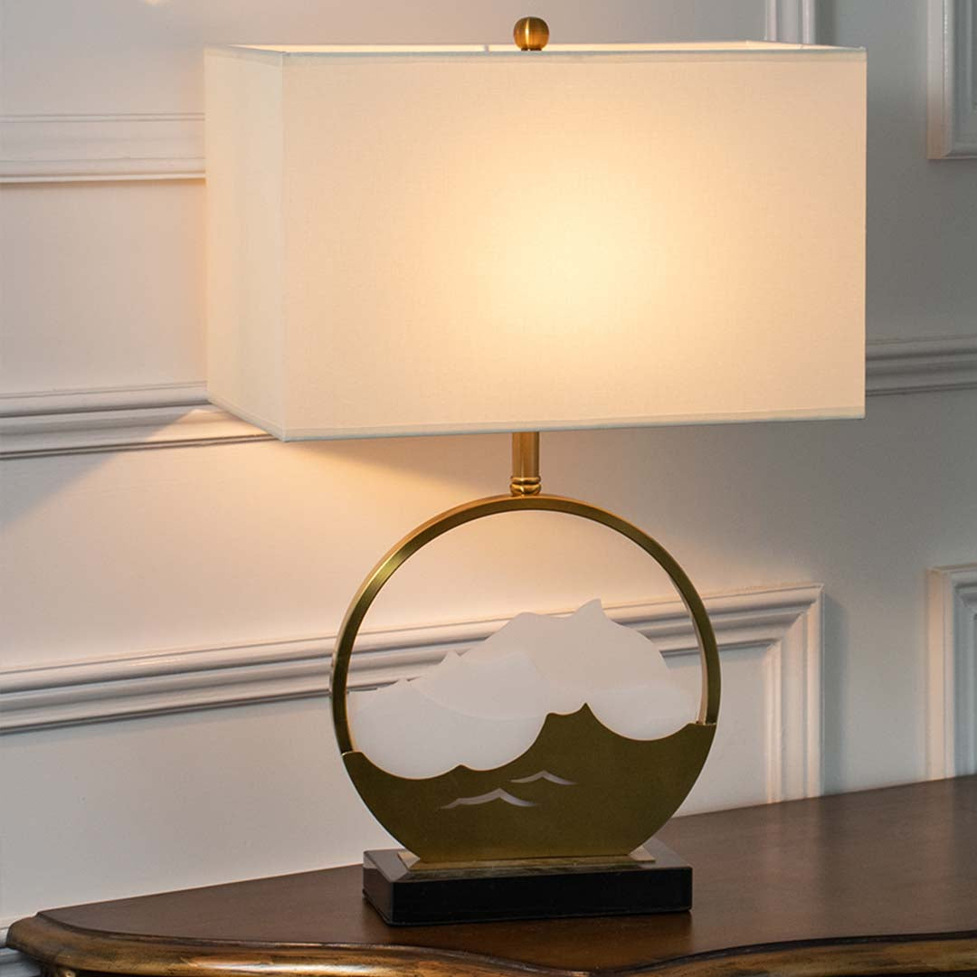 Green glass table lamp with fabric drum shade and gold ring base creating elegant modern ambient lighting indoors.