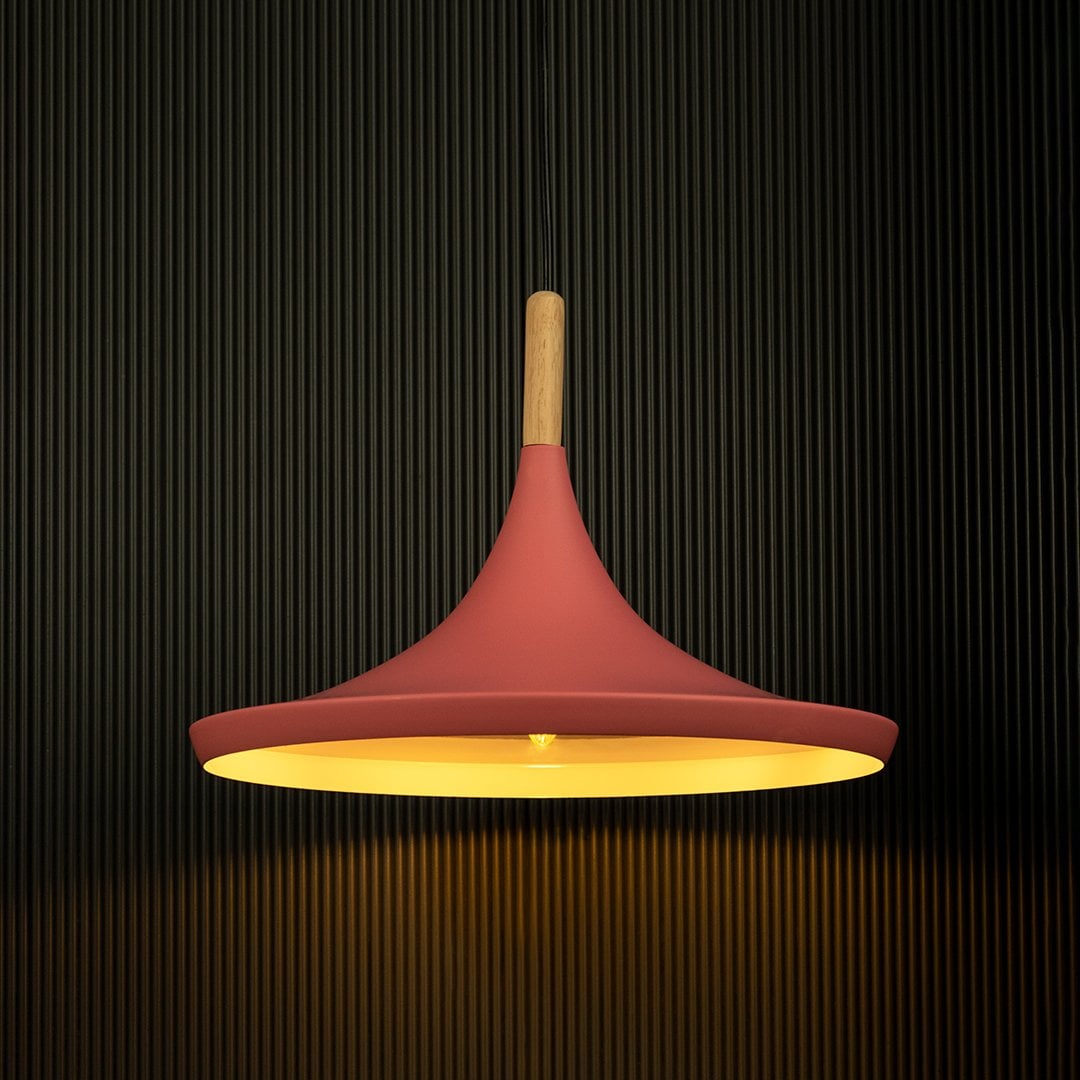 Pink pendant light shining against a dark background emphasizes its elegant form and wooden accents.