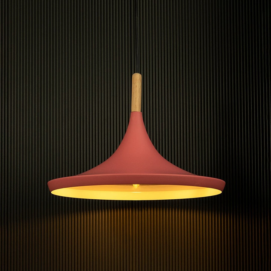Pink pendant light shining against a dark background emphasizes its elegant form and wooden accents.
