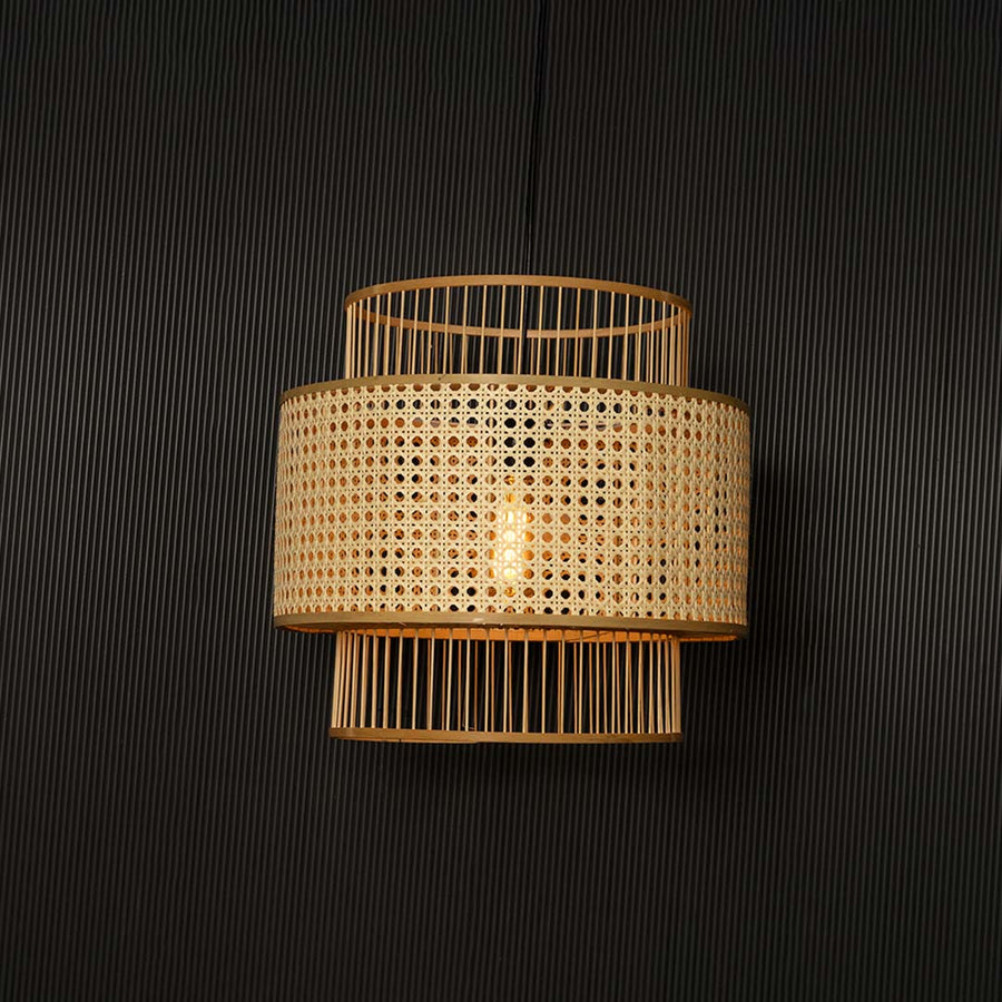 Boho rattan pendant light glowing softly through woven cane shade creating warm ambience on black background.