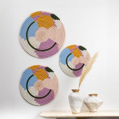 Handwoven multicolor cotton wall plates in pastel blue pink mustard green and cream tones styled in a modern lifestyle setup for elegant decorative living room wall art.