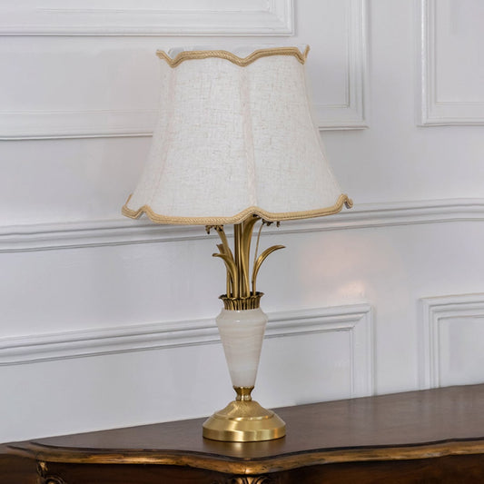 Gold and white marble base table lamp with cream fabric shade turned off against white background home decor table lamp.