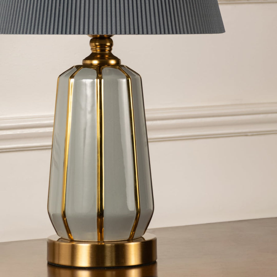 Closeup shot of premium lamp base with golden metal accents and pleated grey shade highlighting craftsmanship and detailing.