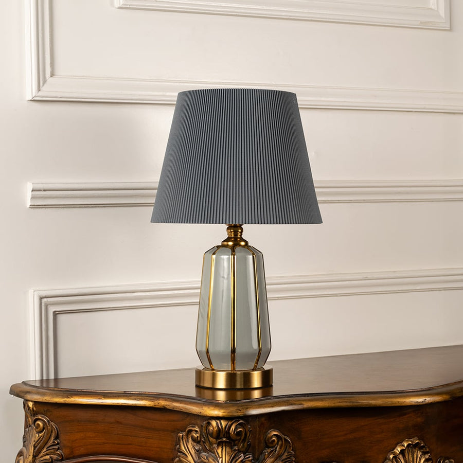 Stylish modern lamp with light off grey fabric lampshade and golden accents against a clean white background.
