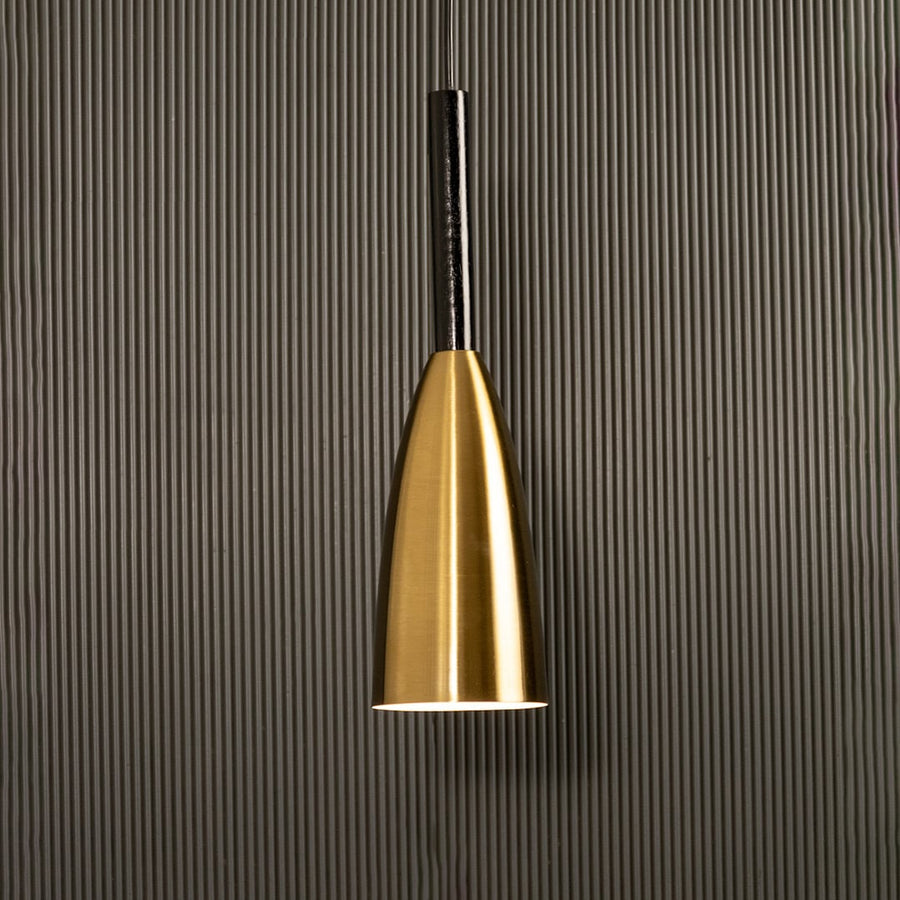 A slim metal pendant light shining softly against a ribbed dark backdrop creating elegant focused illumination and minimal refined modern décor.
