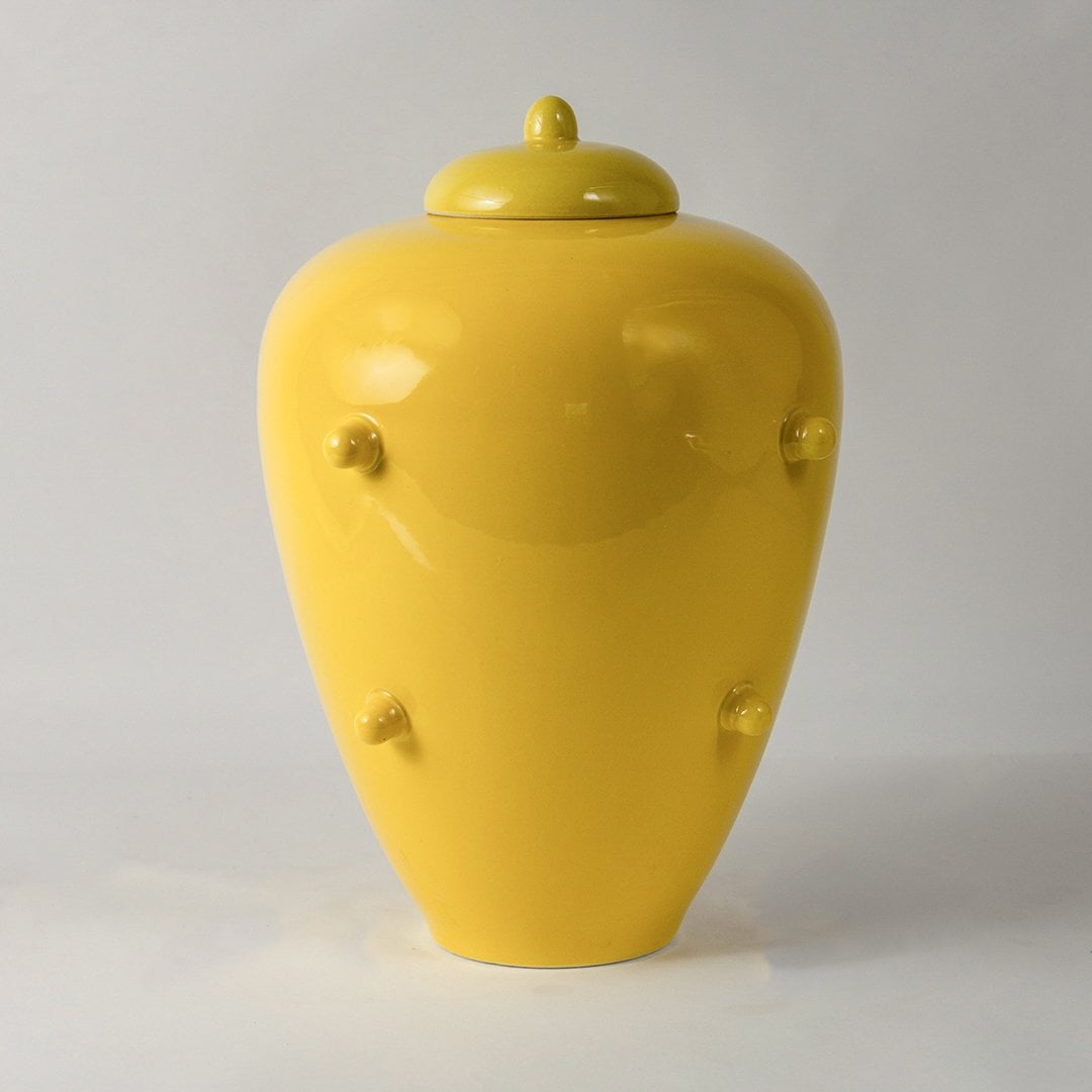 Glossy yellow ceramic decorative jar with lid statement vase for modern interiors living room styling white background view.
