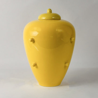 Glossy yellow ceramic decorative jar with lid statement vase for modern interiors living room styling white background view.