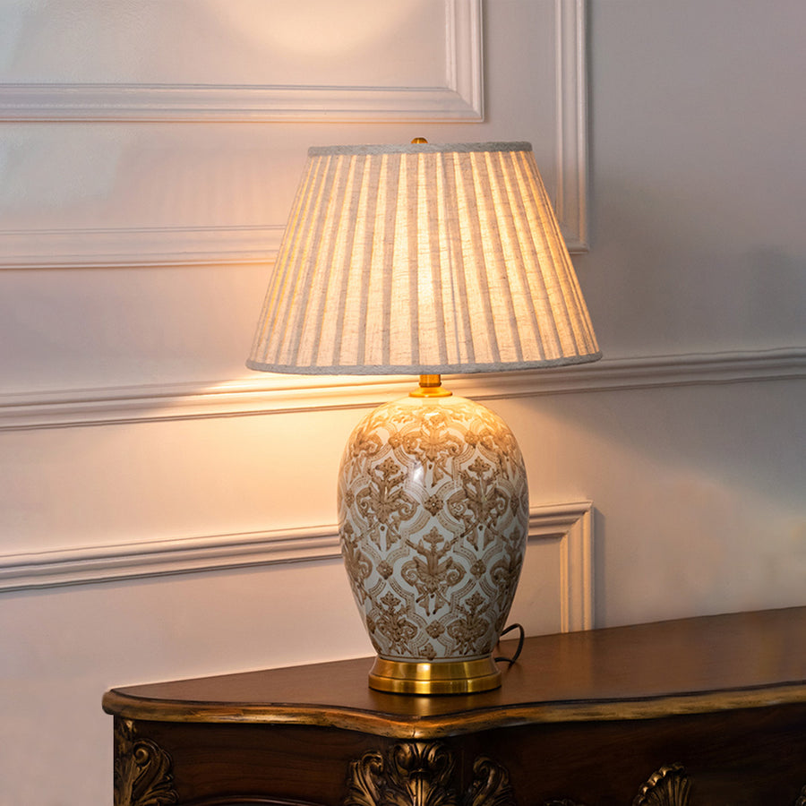 White floral ceramic table lamp with pleated fabric shade displayed on a carved console table offering elegant decor lighting.