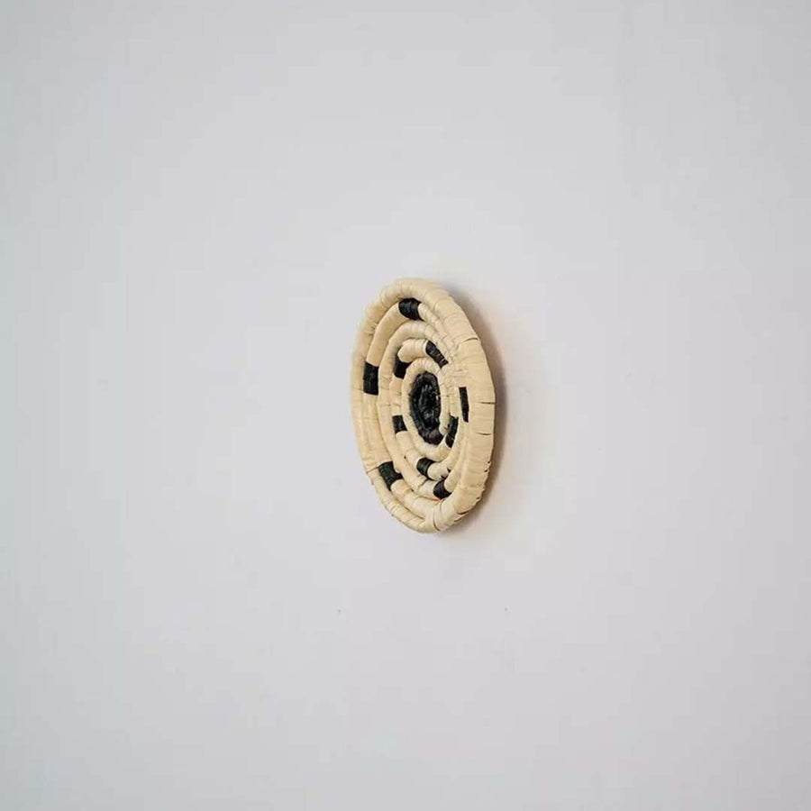 Side profile of handwoven bamboo wall plate in yellow beige shades highlighting detailed weave and natural texture.
