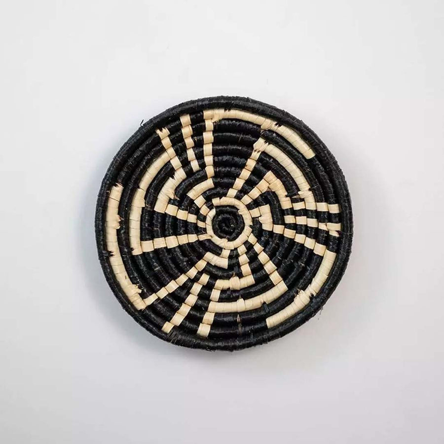Black and natural woven decorative wall basket with spiral pattern for artistic wall styling and modern home decor.