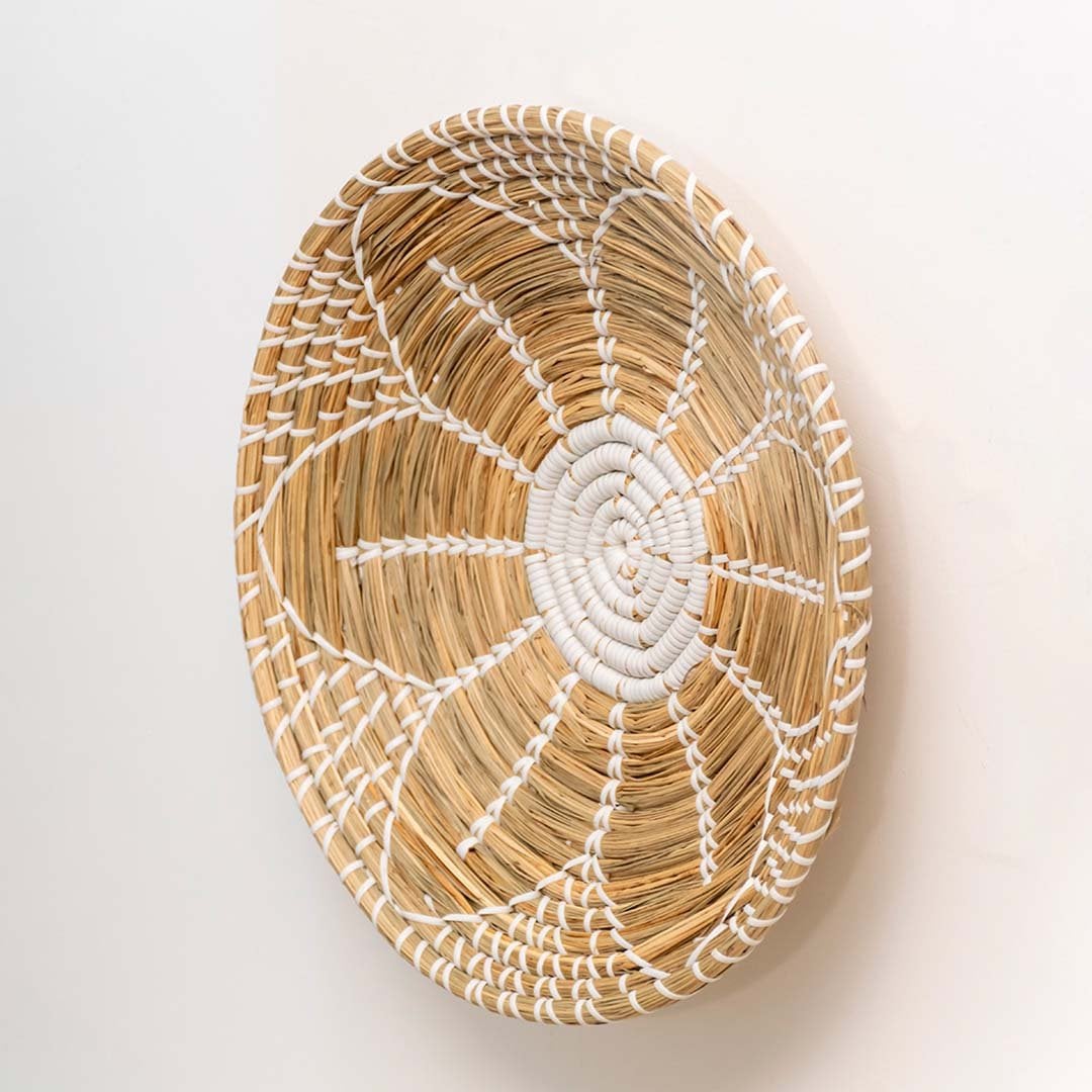 Side view of natural jute woven wall basket with white detailing is a lightweight decorative wall plate for bohemian interiors.