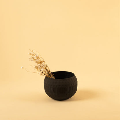 Matte black textured metal bowl with dried stem for minimalist home decor and contemporary interior tabletop accents.