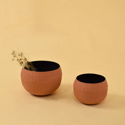 Terracotta planter bowl styled in a warm lifestyle scene as part of a grouped decorative display on a beige backdrop