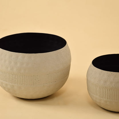 Closeup of small cream round textured pot showing detailed ribbed band and matte black interior for stylish contemporary decor.
