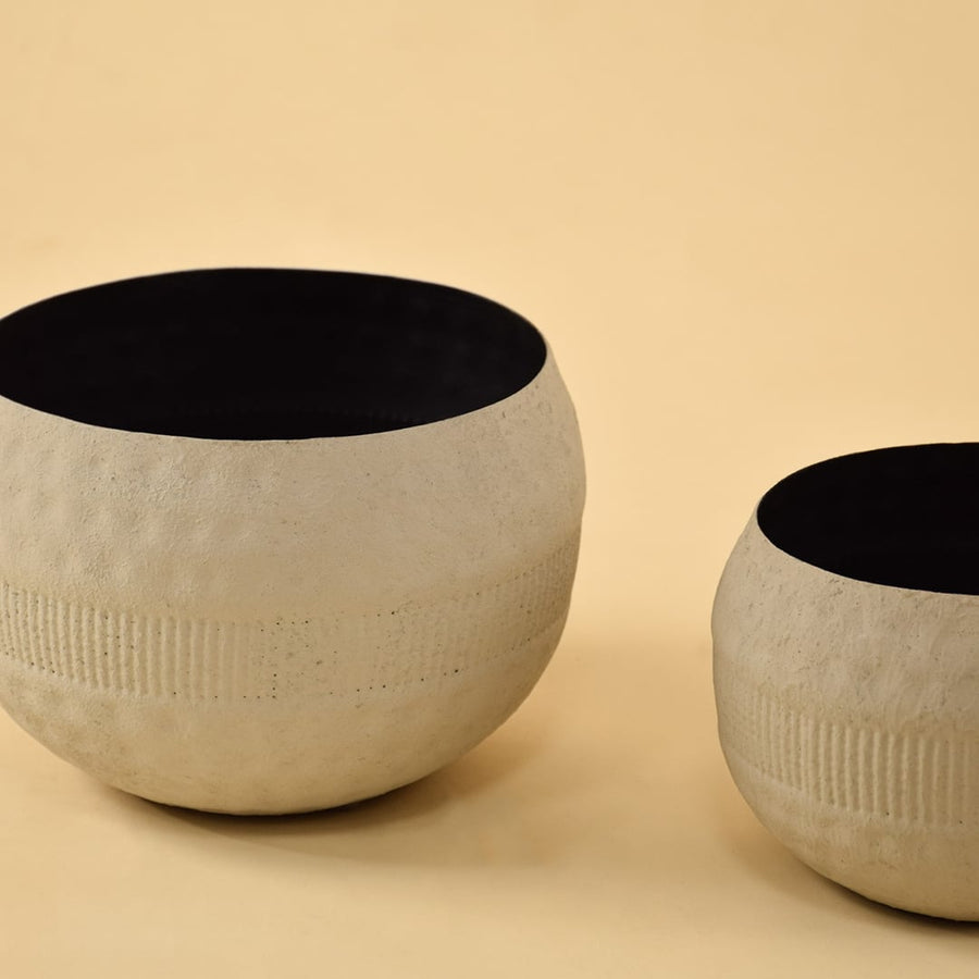 Closeup of small cream round textured pot showing detailed ribbed band and matte black interior for stylish contemporary decor.