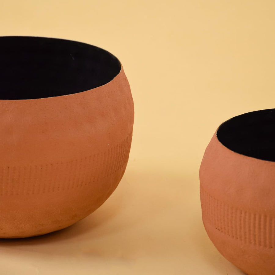 Closeup view of a terracotta textured planter bowl showing its dotted surface pattern and smooth black interior