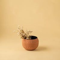 Terracotta textured planter bowl with black interior styled in a warm minimal home setting adding earthy modern decor charm.