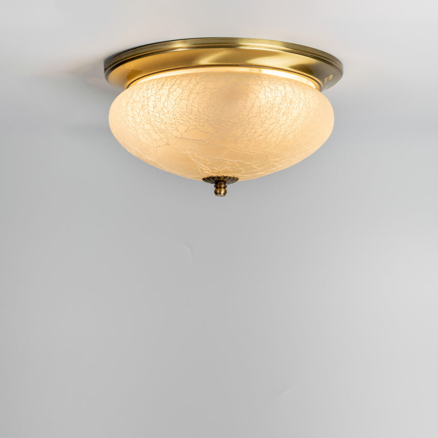 Modern antique brass ceiling light with textured frosted glass shade for elegant bedroom and hallway decor spaces.