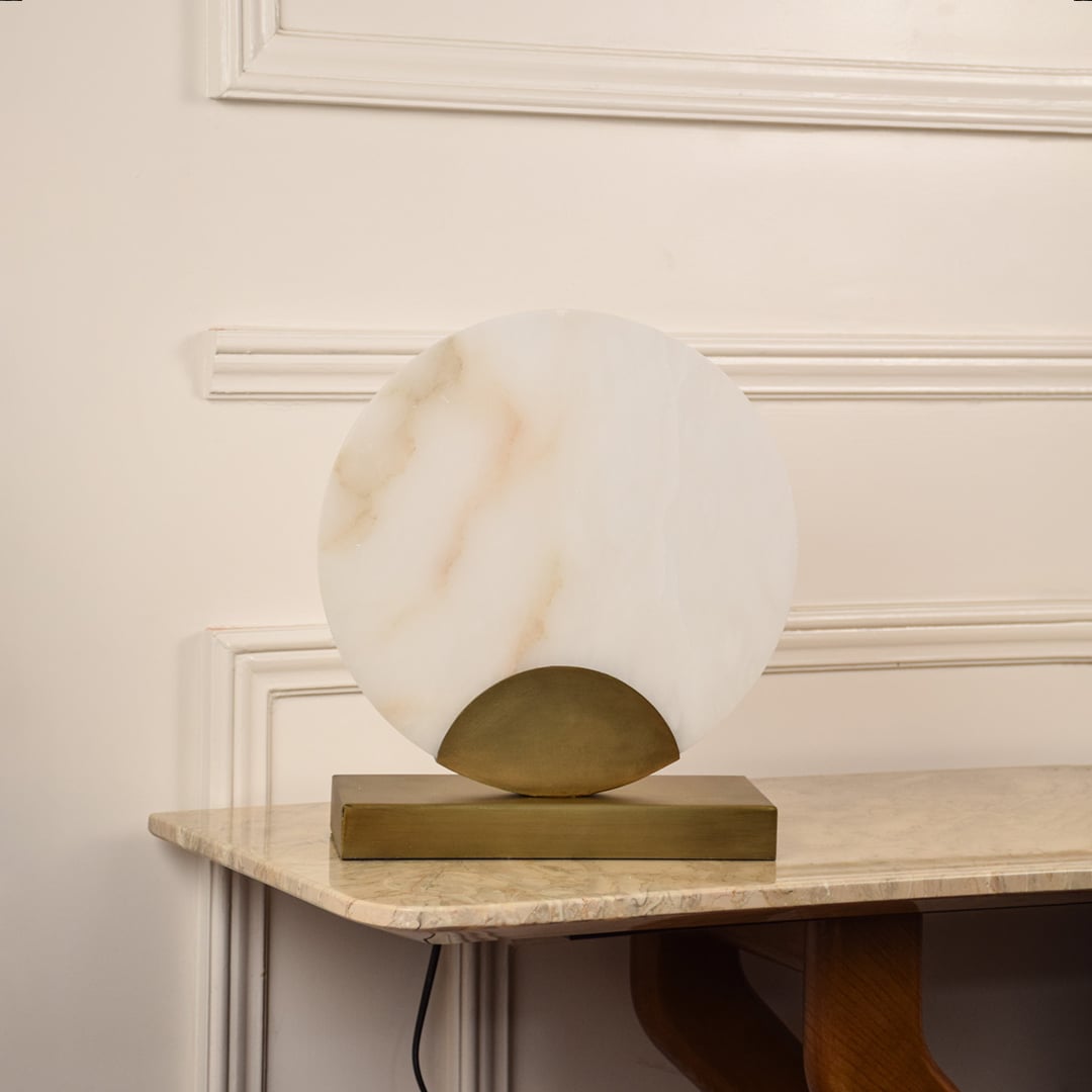 Round marble table lamp unlit on white background featuring gold base and smooth marble finish enhancing minimalist modern interiors.