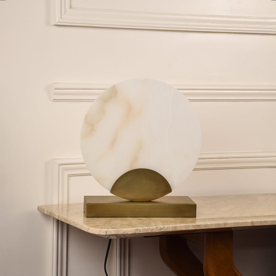 Round marble table lamp unlit on white background featuring gold base and smooth marble finish enhancing minimalist modern interiors.