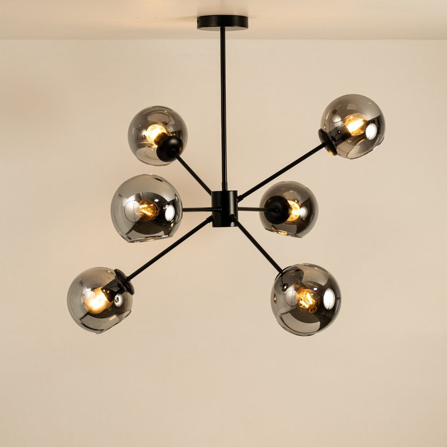 Black and gold metal chandelier with illuminated exposed bulbs creating warm ambient lighting for stylish interiors.