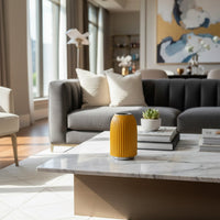 Yellow ribbed ceramic vase styled on a coffee table adding warmth to modern living room decor and interiors.
