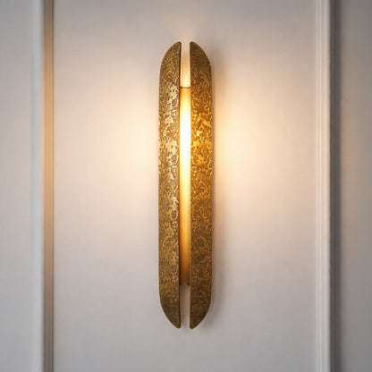 Contemporary gold wall sconce with glowing textured glass cylinder on neutral wall background ideal for elegant bedroom or hallway lighting.