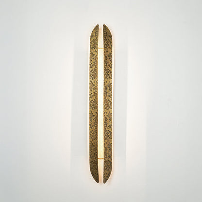 Gold wall light with elongated textured metal design mounted on neutral wall background ideal for modern luxury interior decor lighting.