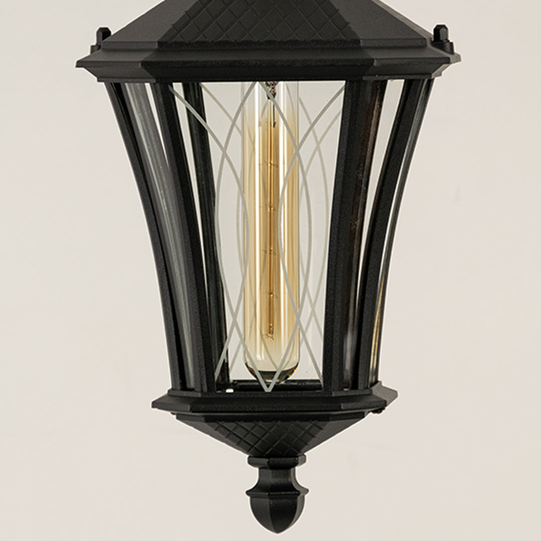 Closeup of black metal outdoor lantern with clear glass panels and bulb on white background ideal for premium exterior decor lighting.