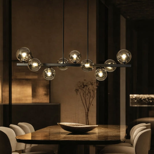 Smoked glass globe chandelier above dining table creating warm ambient lighting for modern luxury dining room interiors.