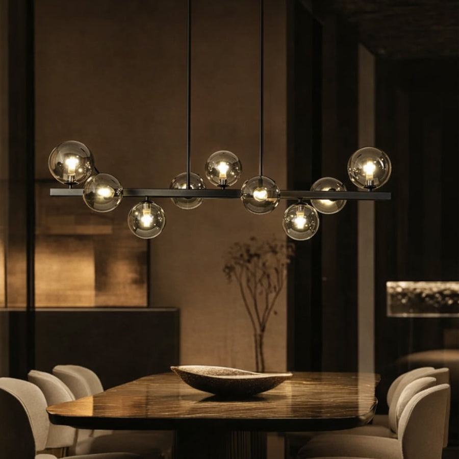 Smoked glass globe chandelier above dining table creating warm ambient lighting for modern luxury dining room interiors.