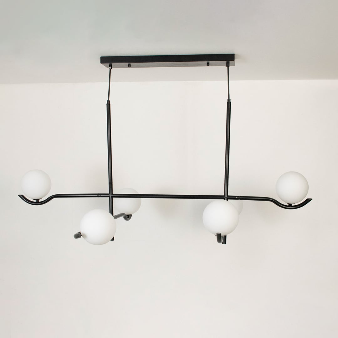 Black metal chandelier with white globes shown on a bright white background with lights turned off for a minimal look.