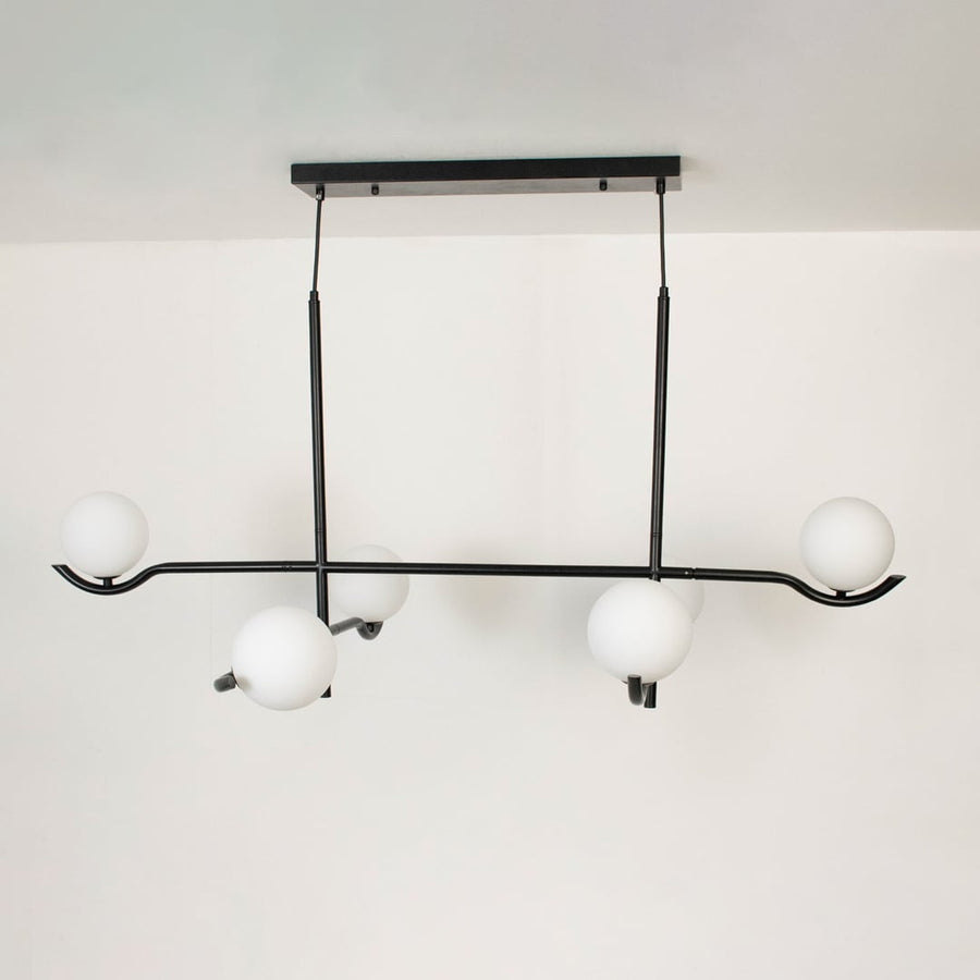 Black metal chandelier with white globes shown on a bright white background with lights turned off for a minimal look.