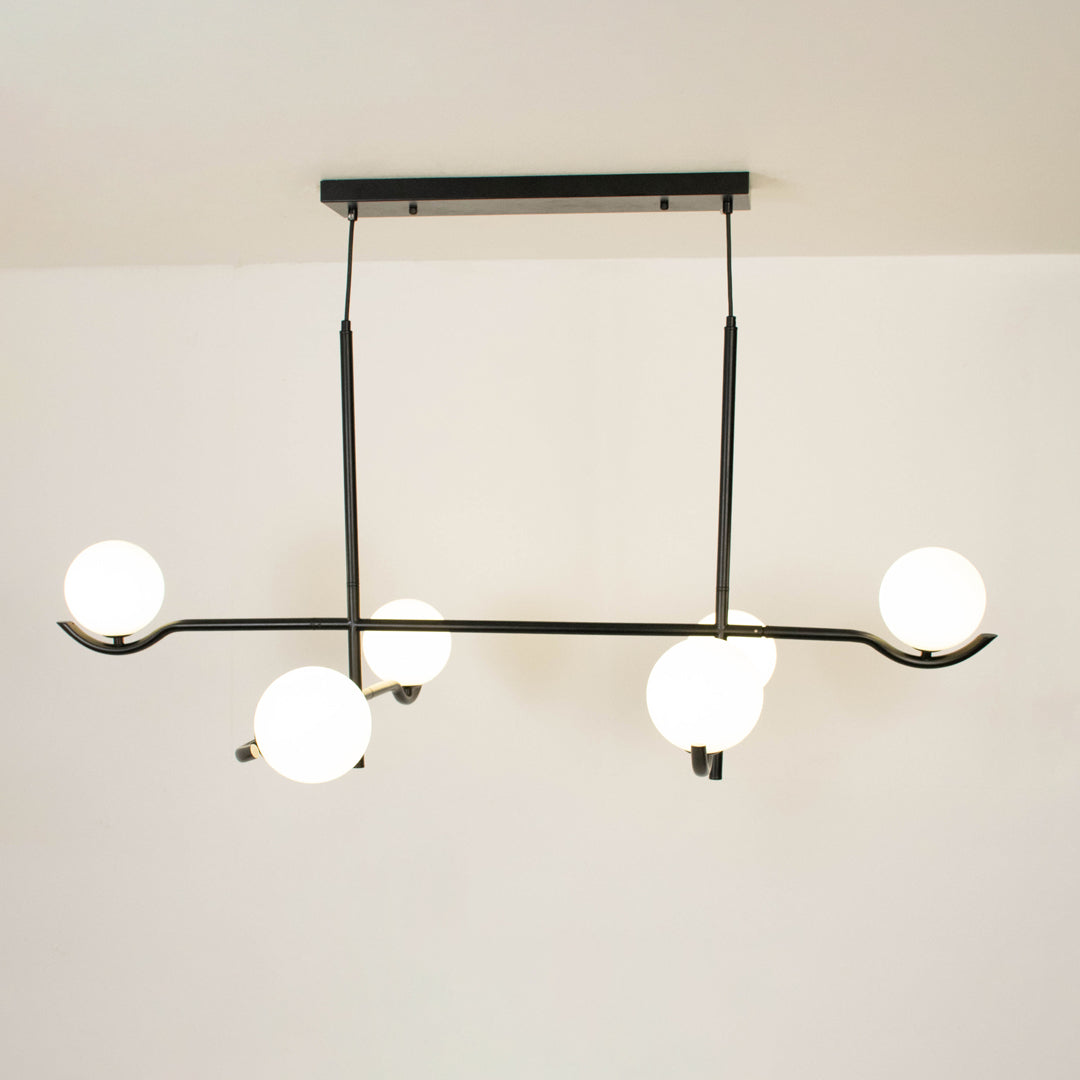 Black metal chandelier with frosted glass globe shades creating elegant ambient lighting for modern interior spaces.