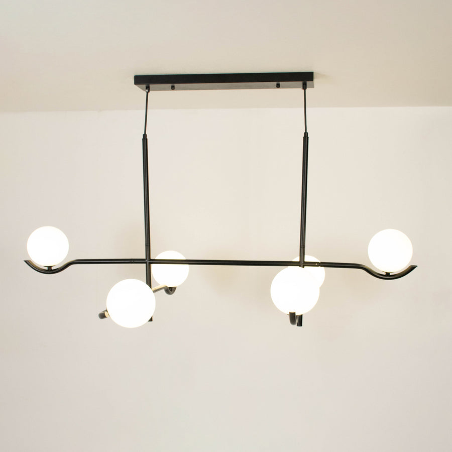 Black metal chandelier with frosted glass globe shades creating elegant ambient lighting for modern interior spaces.