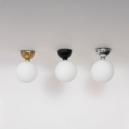 Collection of ceiling lights in black gold and chrome finish with frosted glass globe shades shown off on background.