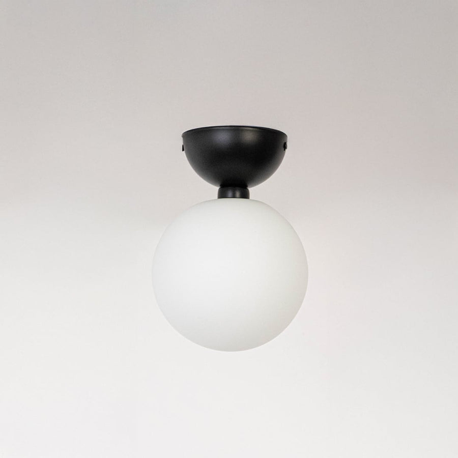 Ceiling light with matte black base and frosted glass globe shade shown off on plain white background.